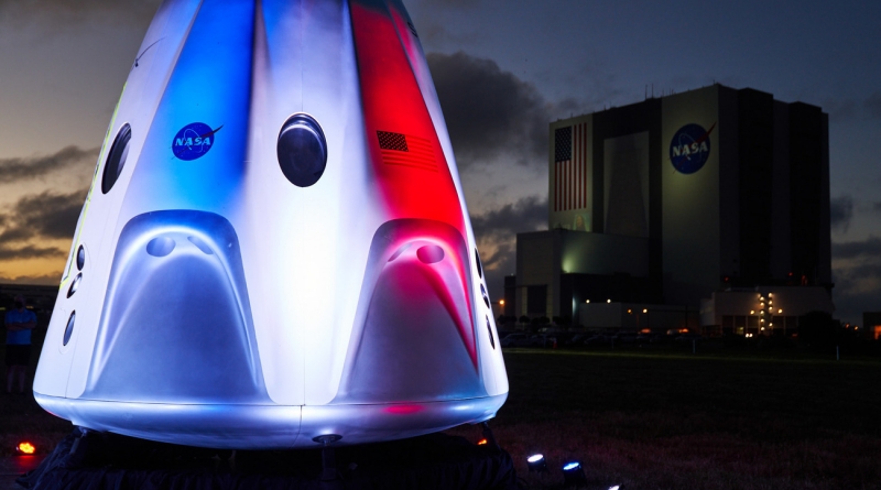 A mockup Crew Dragon at Kennedy Space Center is lit up in red, white and blue prior to the launch of SpaceX's first operational crew rotation mission.  Photo credit: Jared Haworth / We Report Space